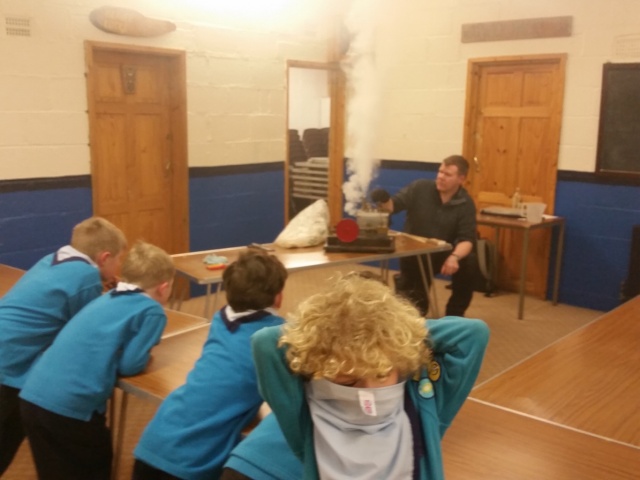 Four beaver scouts are waiting for food while the volunteer is cooking.
