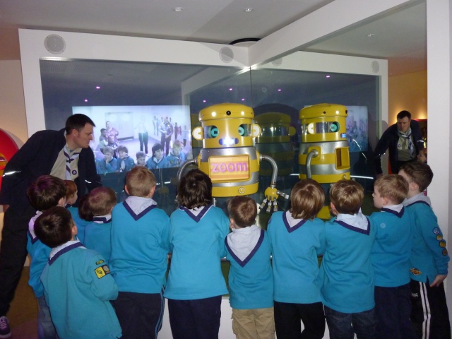 beaver scouts are looking at a robot led by a volunteer.