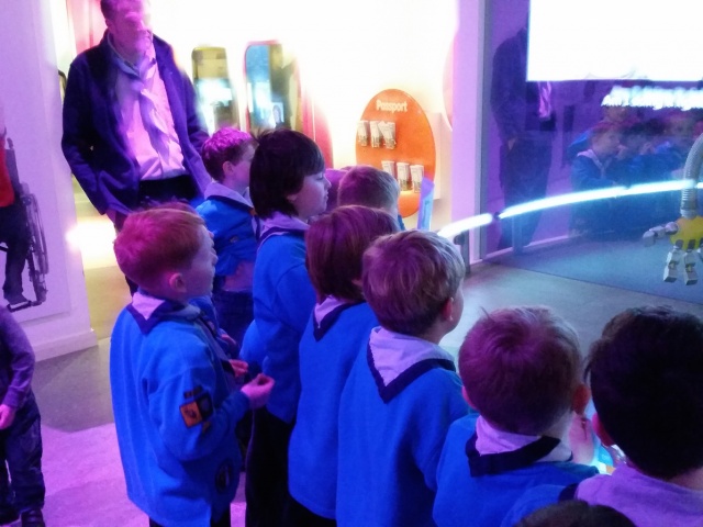 A group of beaver scouts are looking at a robot carefully.